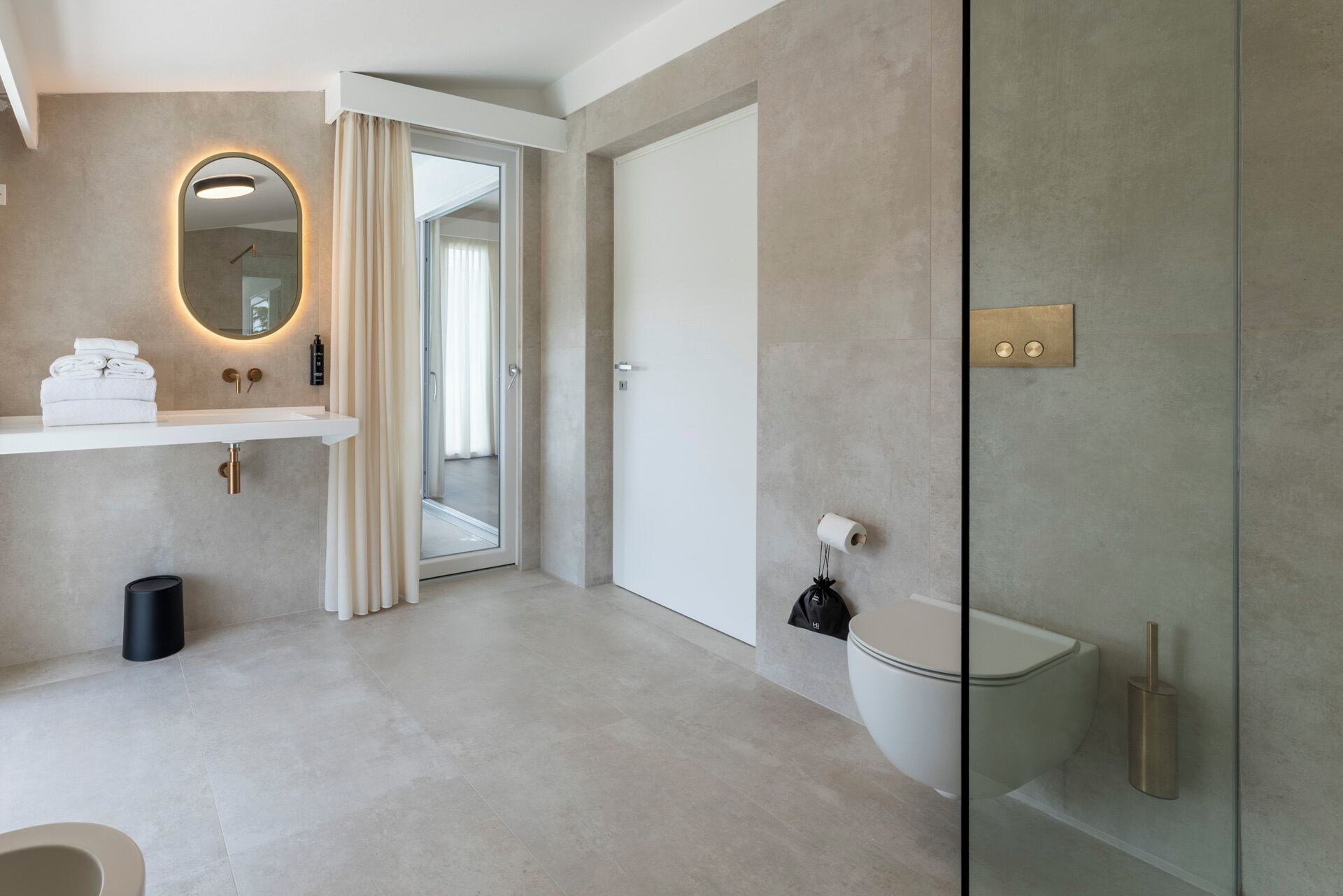 Een moderne badkamer met een douchecabine van glas, een wit toilet en een wastafel met een handdoekhouder.