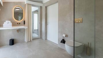 Een moderne badkamer met een douchecabine van glas, een wit toilet en een wastafel met een handdoekhouder.