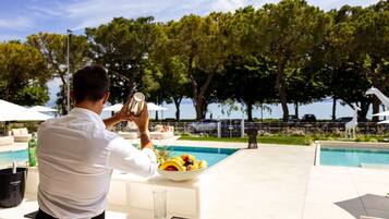Una persona che scatta una foto con una macchina fotografica, una piscina e un'area pranzo con una ciotola di frutta.