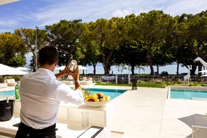 Una persona che scatta una foto con una macchina fotografica, una piscina e un'area pranzo con una ciotola di frutta.