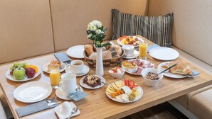 Una mesa de desayuno con diferentes platillos, como frutas, bollería y bebidas.