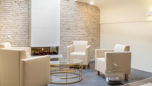 Un área de descanso moderna con pared de ladrillo, una mesa de centro de vidrio y sillones de cuero.