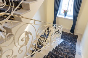 A marble staircase with ornate white metal railings and a window with curtains. - Galerie Hotel Bad Reichenhall (Bad Reichenhall)