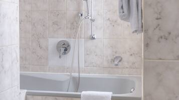 Une salle de bain avec une baignoire, une douche et un porte-serviettes.