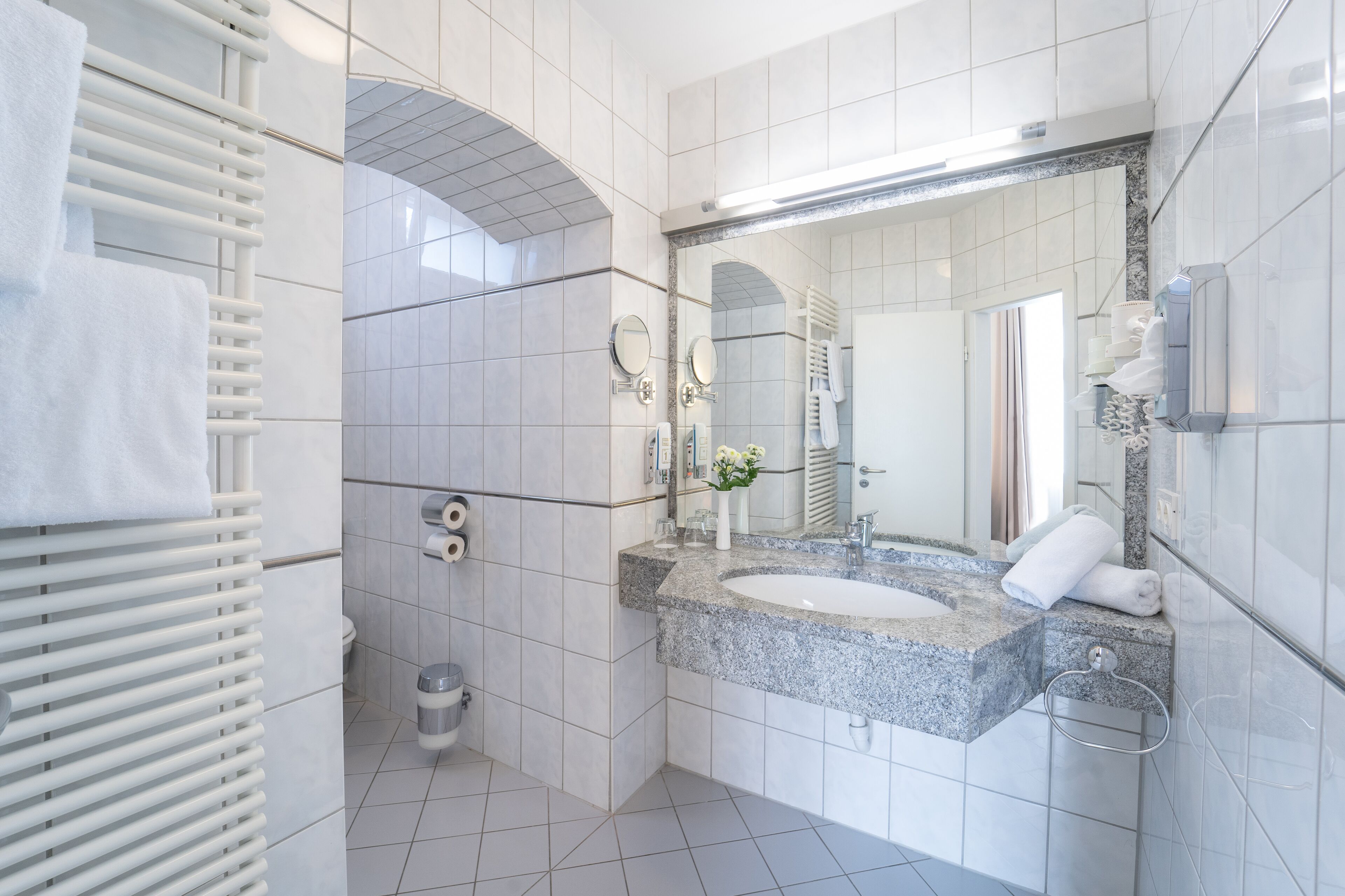 Ein modernes Badezimmer mit einem Doppelwaschbecken, einem großen Spiegel und einem Handtuchhalter.