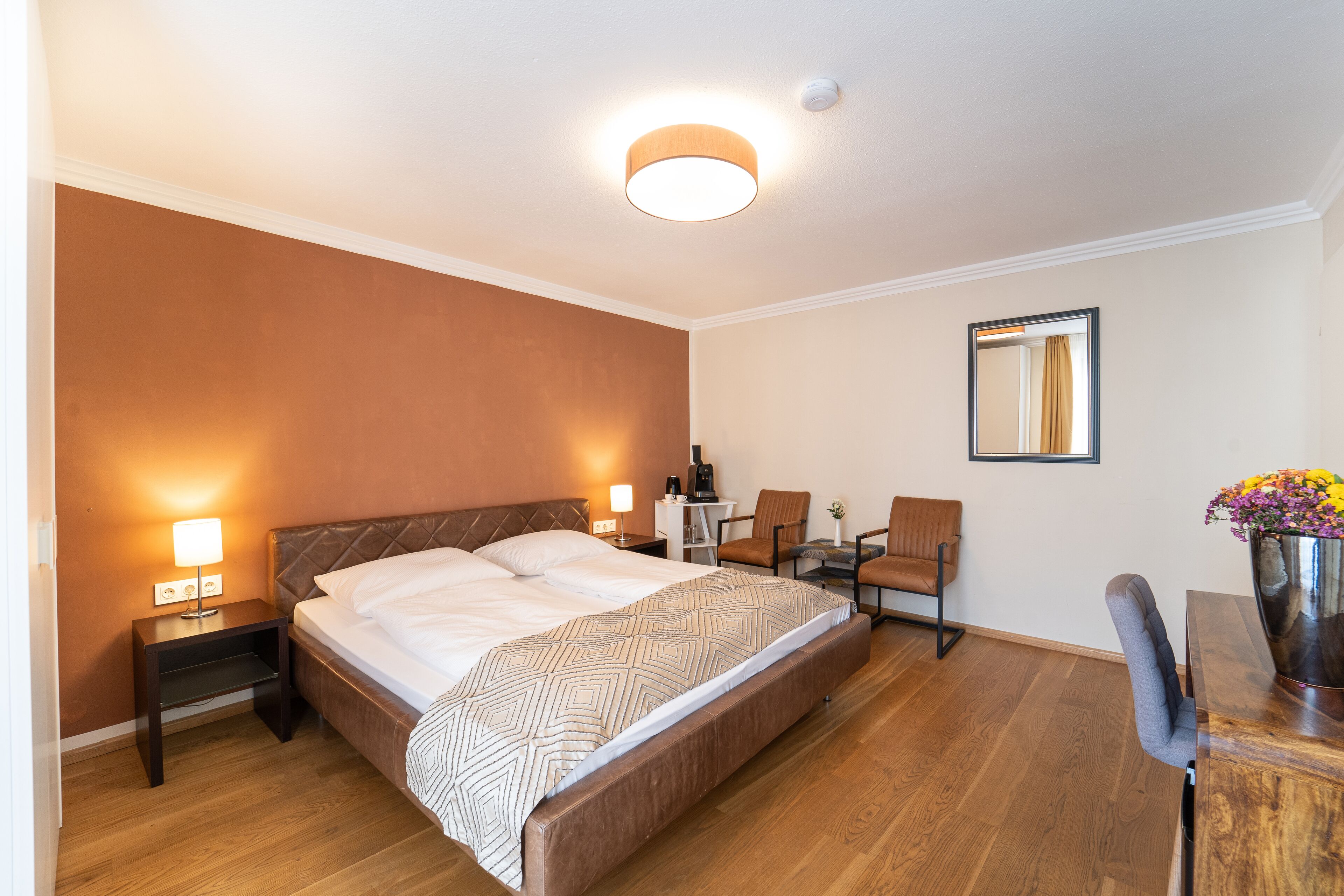 A hotel room with a large bed, bedside tables, a desk, and a chair.