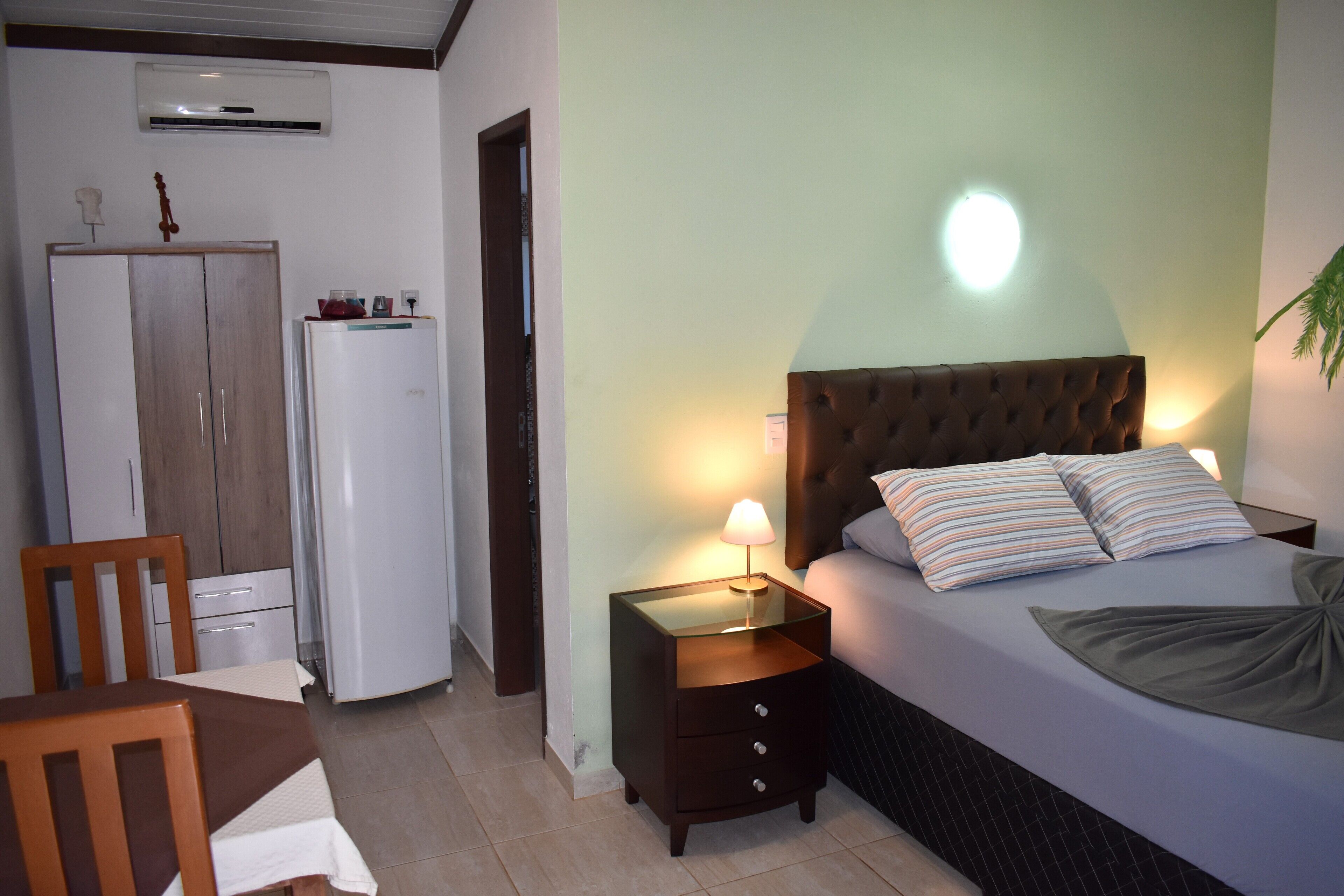 Un dormitorio con cama, mesita de noche, lámpara y armario.