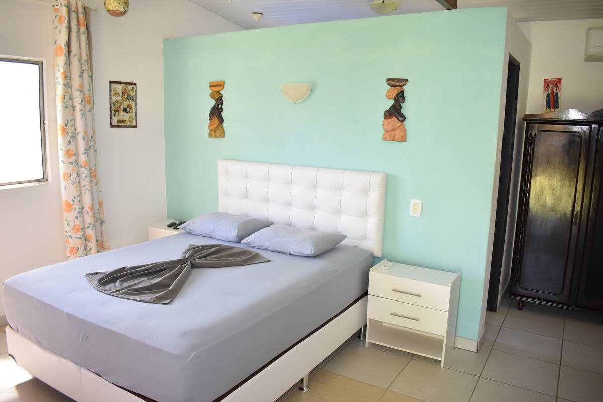 Une chambre à coucher comprenant un lit, des tables de chevet, une commode et une armoire.