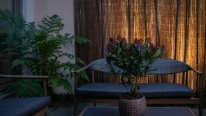 Un espacio de descanso con una mesa, sillas, una planta en maceta y un fondo de bambú.
