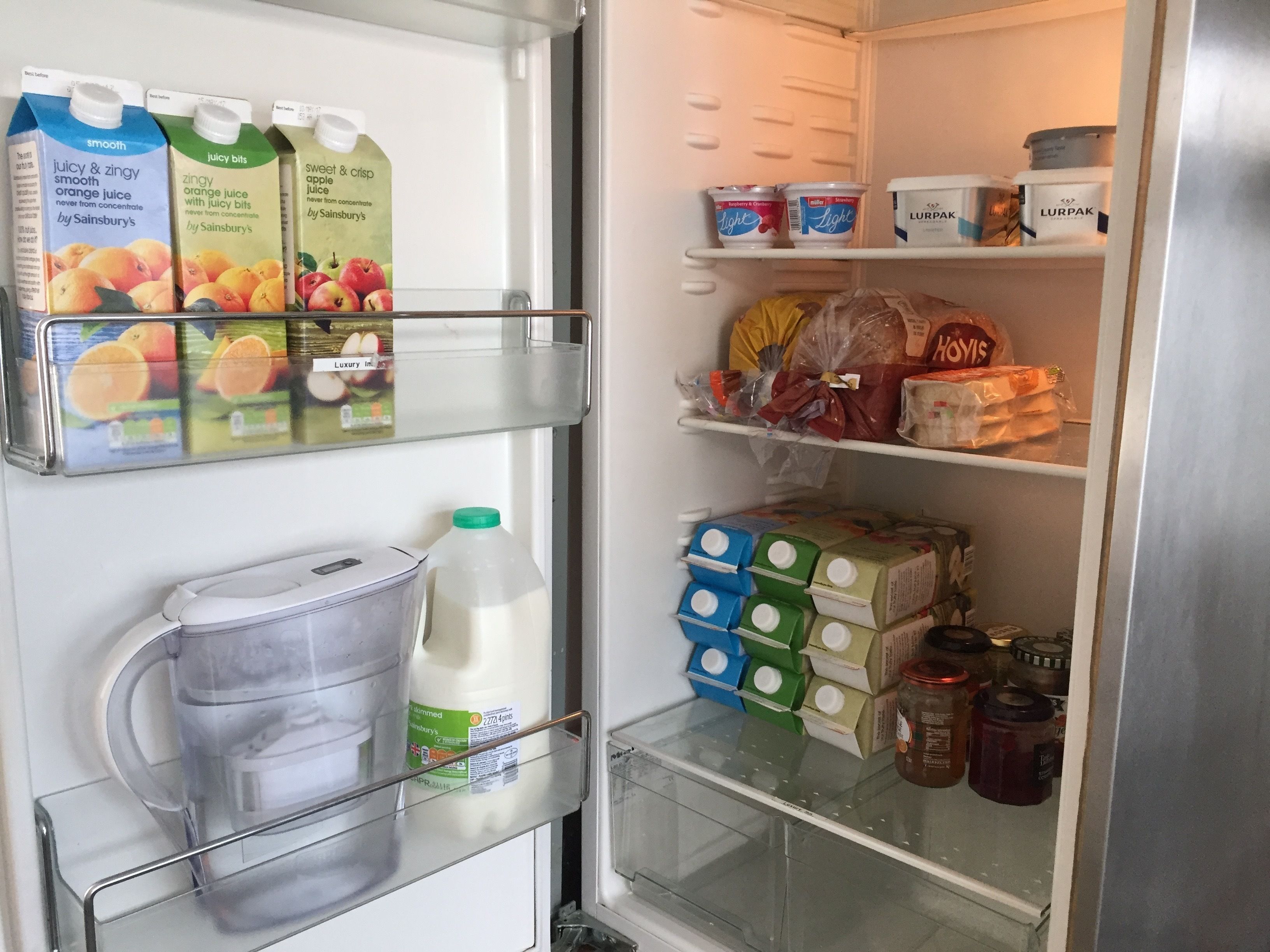 A refrigerator stocked with various food items including milk, juice, and packaged goods.