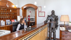 Ein Empfangstresen mit Holzoptik, eine Ritterstatue und ein Feuerlöscher im Hintergrund.