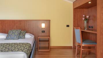 Een hotelkamer met twee bedden, een nachtkastje, een houten stoel en een klein plankje met bloemen.