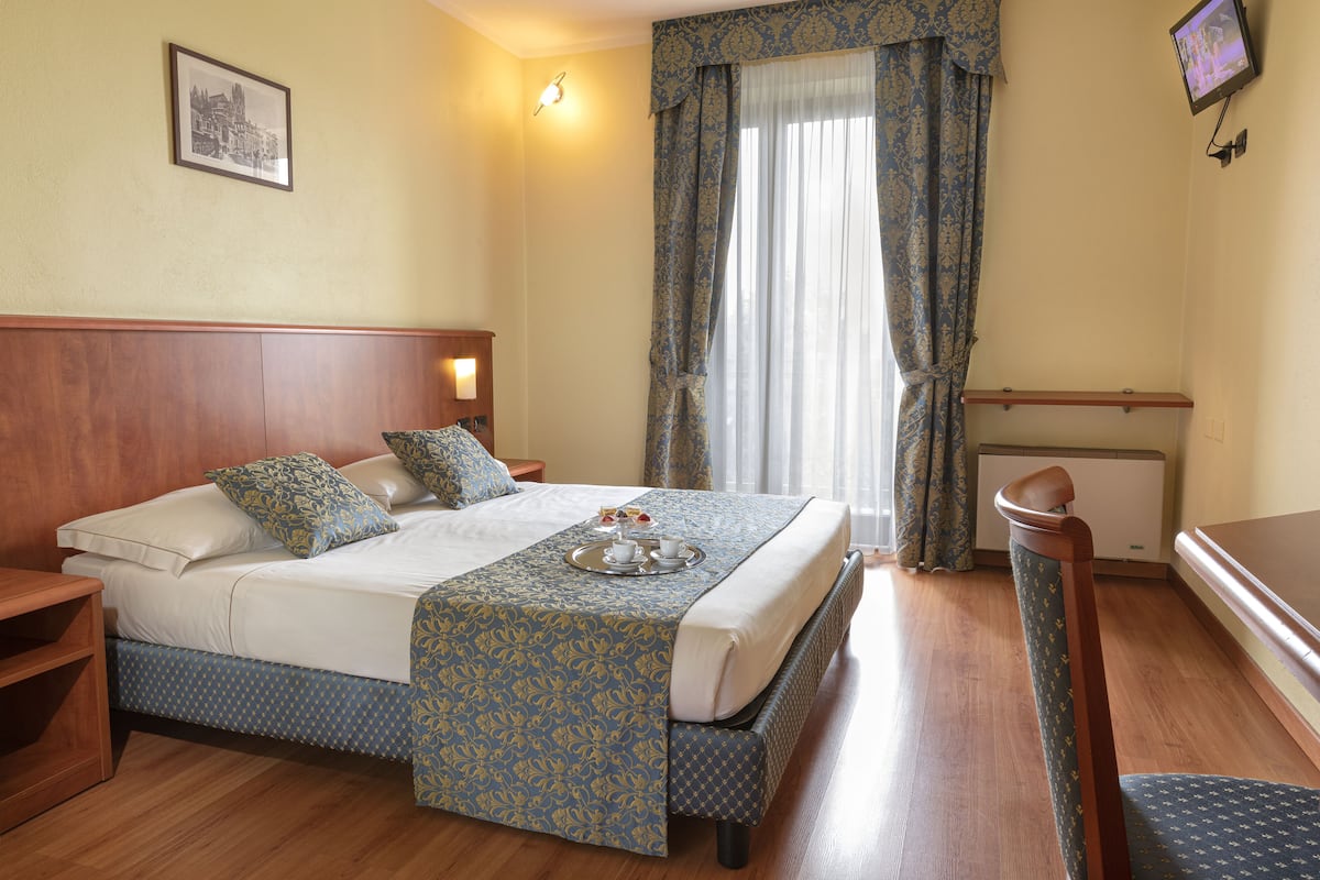 Une chambre d’hôtel équipée d’un lit, d’une table de chevet et d’un téléviseur fixé au mur.