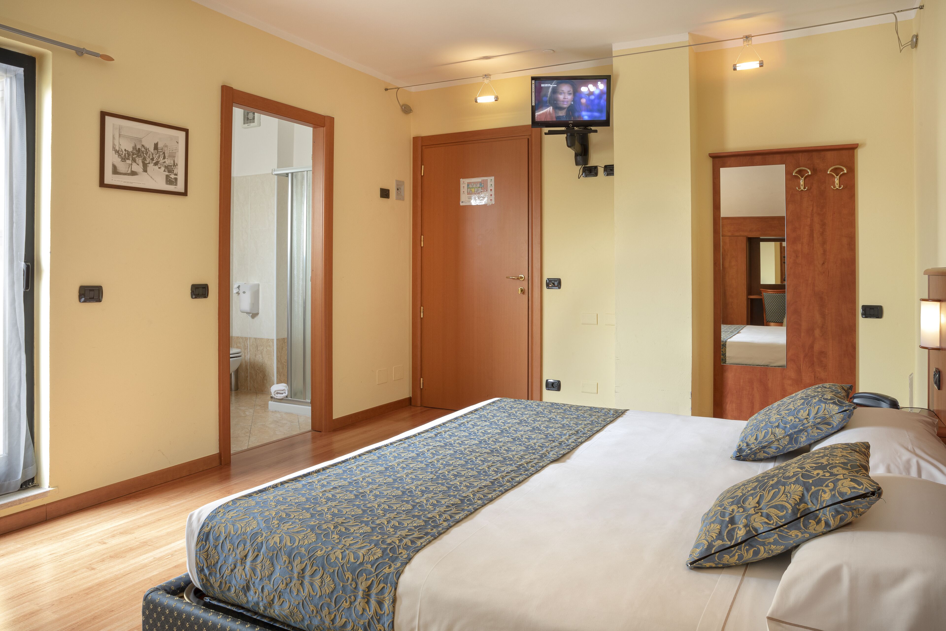A hotel room with a large bed, a television mounted on the wall, and a bathroom visible through an open door.