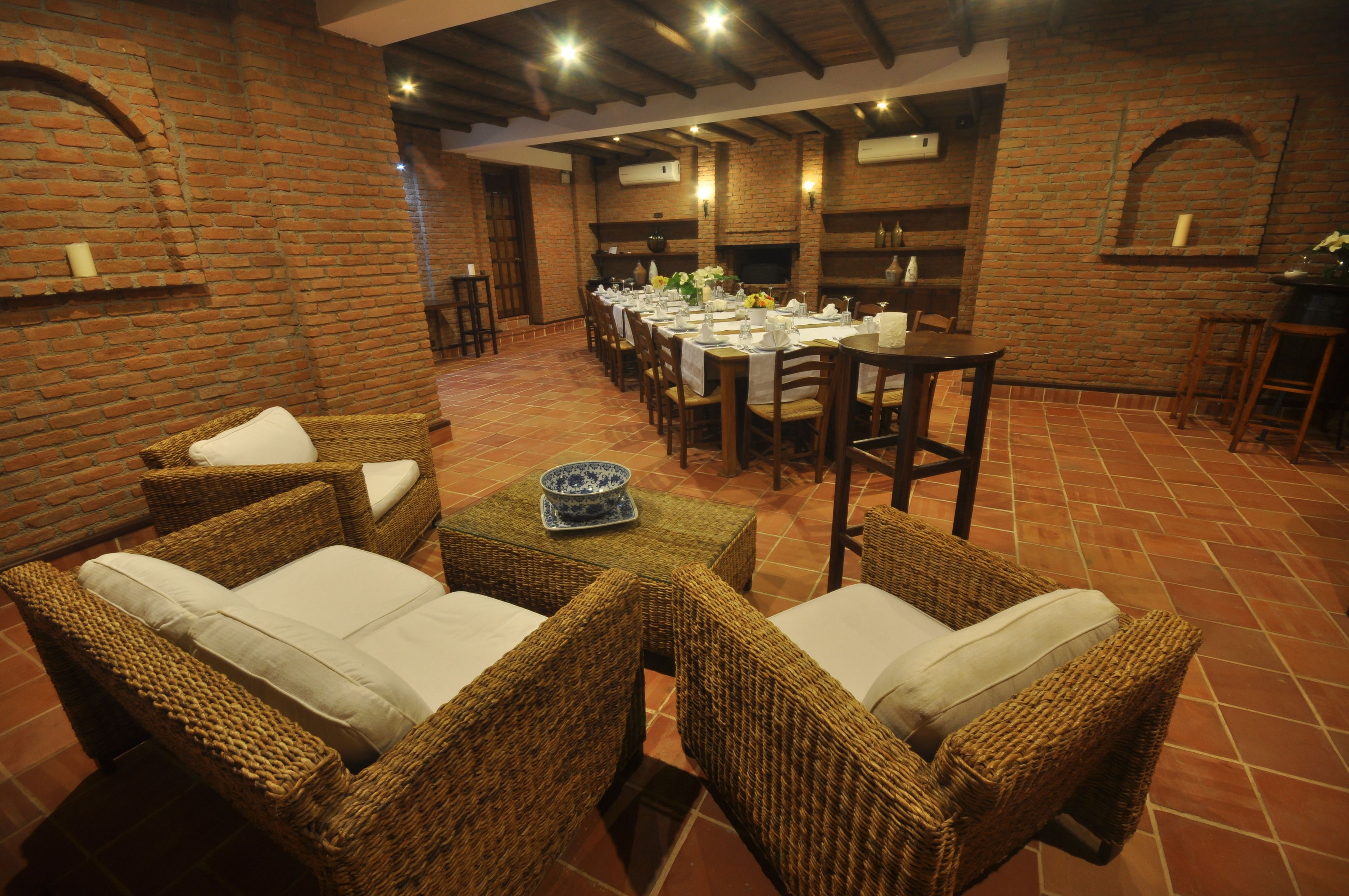 A dining area with wicker furniture and a brick wall.