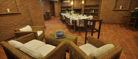 A dining area with wicker furniture and a brick wall.