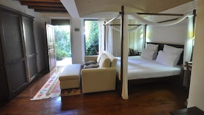 Un dormitorio con una cama con dosel, un sofá y vistas a zonas verdes.