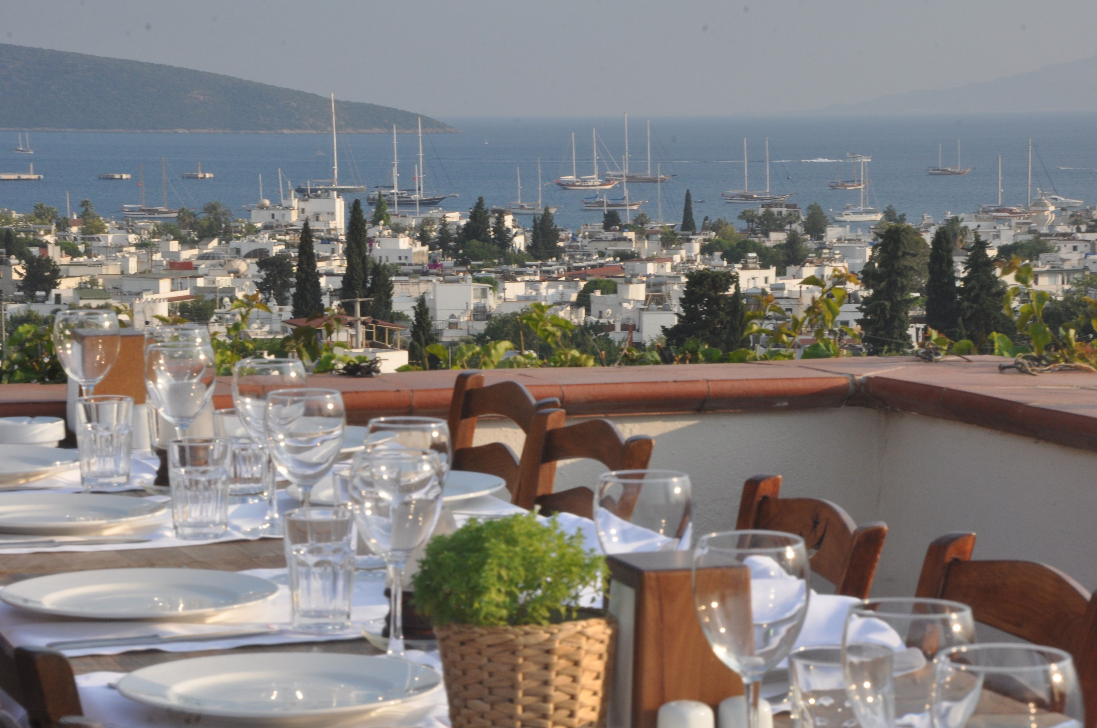 Mesa lista para comer con vista a un puerto deportivo y barcos.