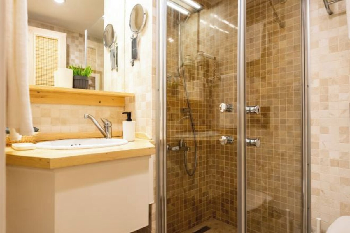 A bathroom with a glass-enclosed shower, a sink with a mirror, and a towel rack.