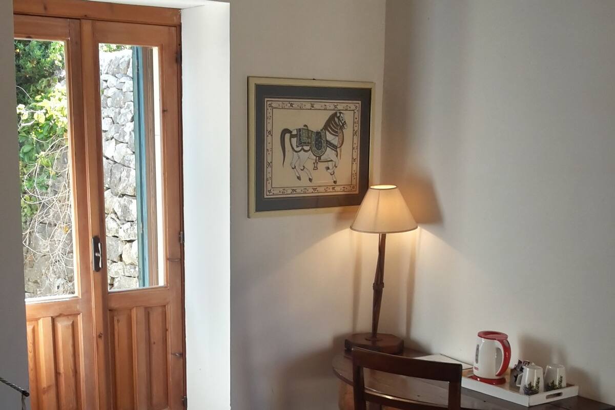 Una stanza accogliente con una porta in legno, un tavolo con una lampada e un quadro appeso al muro.