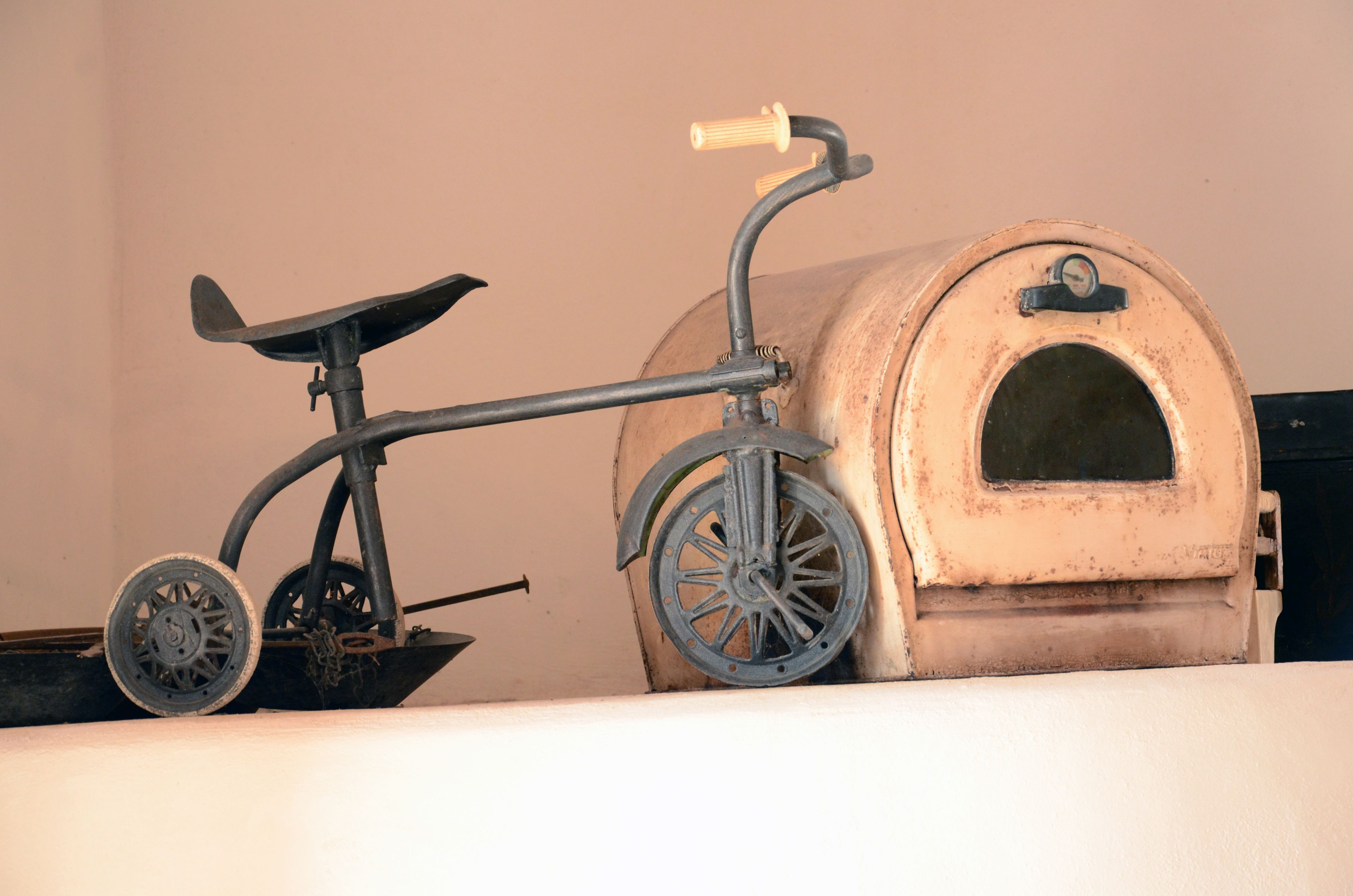 A vintage bicycle with a front basket and a small, round, barrel-like object with a handle.