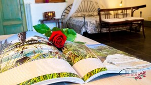 A room with a bed, a bench, and a book with a red rose on it.