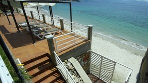 A beachside terrace with outdoor seating and a view of the sea.