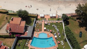 An aerial view of a hotel with a swimming pool, beach access, and a landscaped garden.