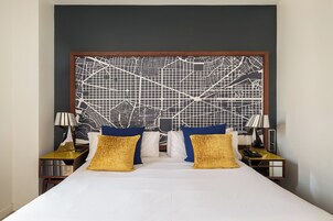 A hotel room with a large bed, two nightstands, a wall map, and decorative pillows.