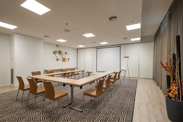 A conference room with a long table, chairs, a projector, and a screen. - Naitly Barcelona Poblenou (Barcelona)