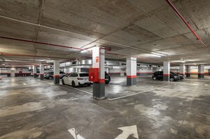 A multi-level underground parking garage with concrete pillars and directional arrows on the floor.