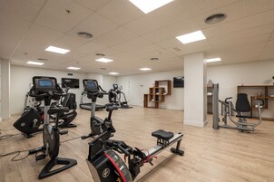 Una palestra con diverse attrezzature per l'esercizio fisico, tra cui tapis roulant, cyclette e macchinari per pesi.