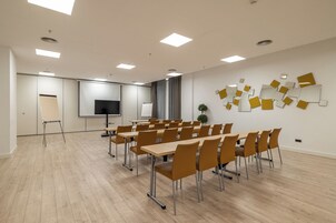 A conference room with a large screen, whiteboard, and a wall with abstract art.