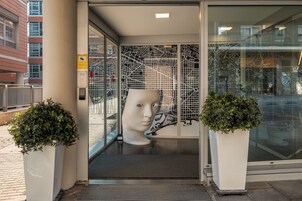 A modern building entrance with a glass door, a metal gate, and a large abstract sculpture.