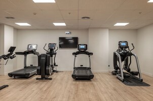 A gym with three treadmills, a stationary bike, and a rowing machine.