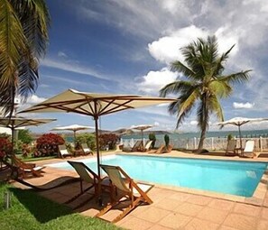 Una piscina al aire libre, sombrillas, sillones reclinables de piscina