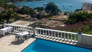 A pool with a view of the sea, surrounded by buildings and greenery. - Casagrande Hotel Boutique (Búzios)