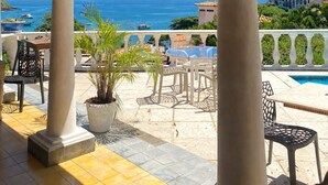 A covered outdoor area with columns, a pool, and a view of the sea. - Casagrande Hotel Boutique (Búzios)