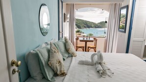 A bedroom with a bed, pillows, a mirror, and a view of the sea. - Casagrande Hotel Boutique (Búzios)