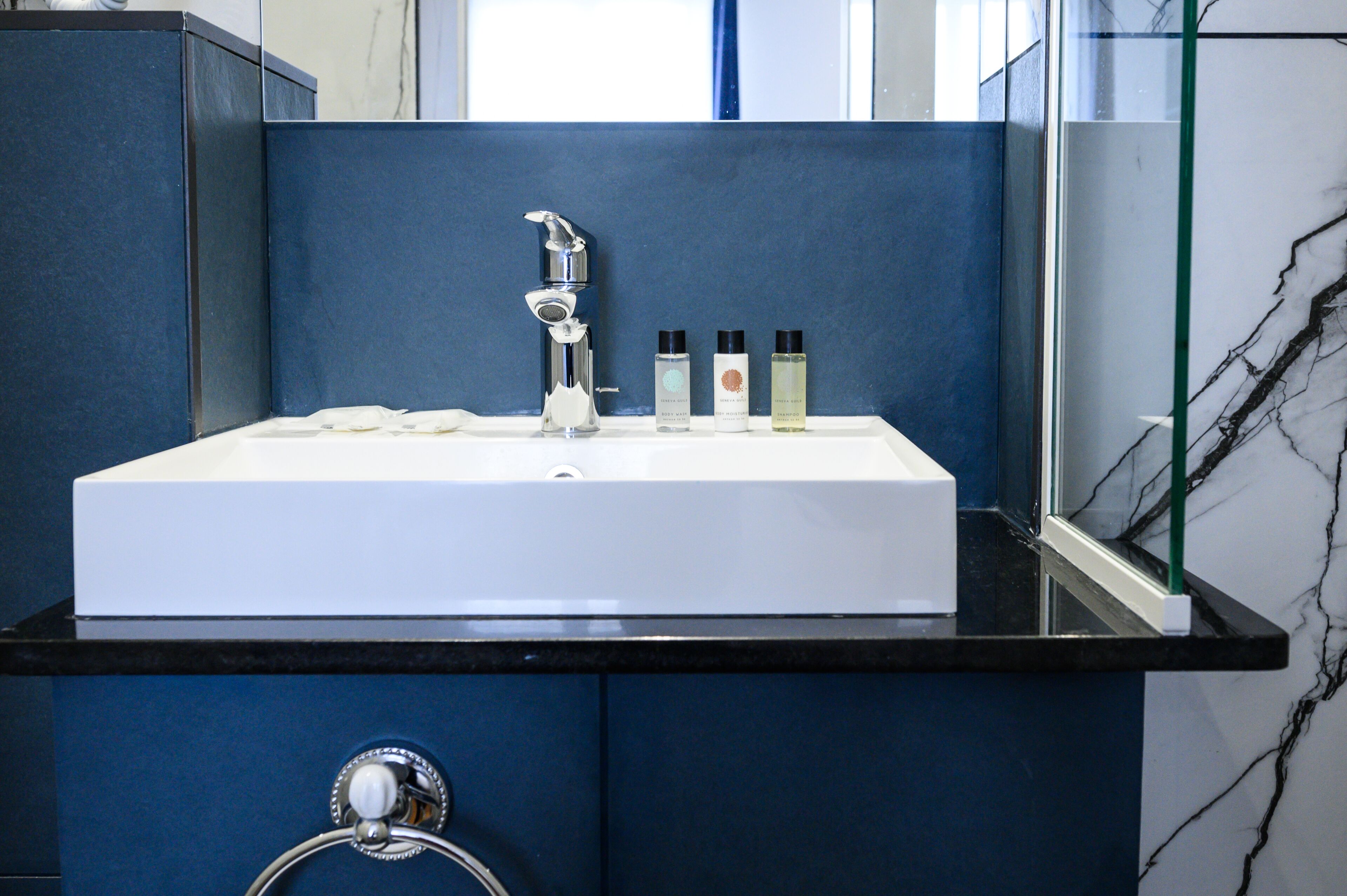 A bathroom with a white sink, blue cabinets, and a glass shower enclosure.