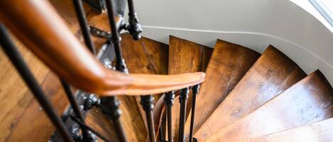 A wooden spiral staircase with metal balusters and a handrail.