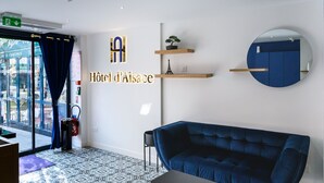 Un intérieur d’hôtel moderne avec un canapé bleu, des carreaux de sol à motifs et un miroir fixé au mur.