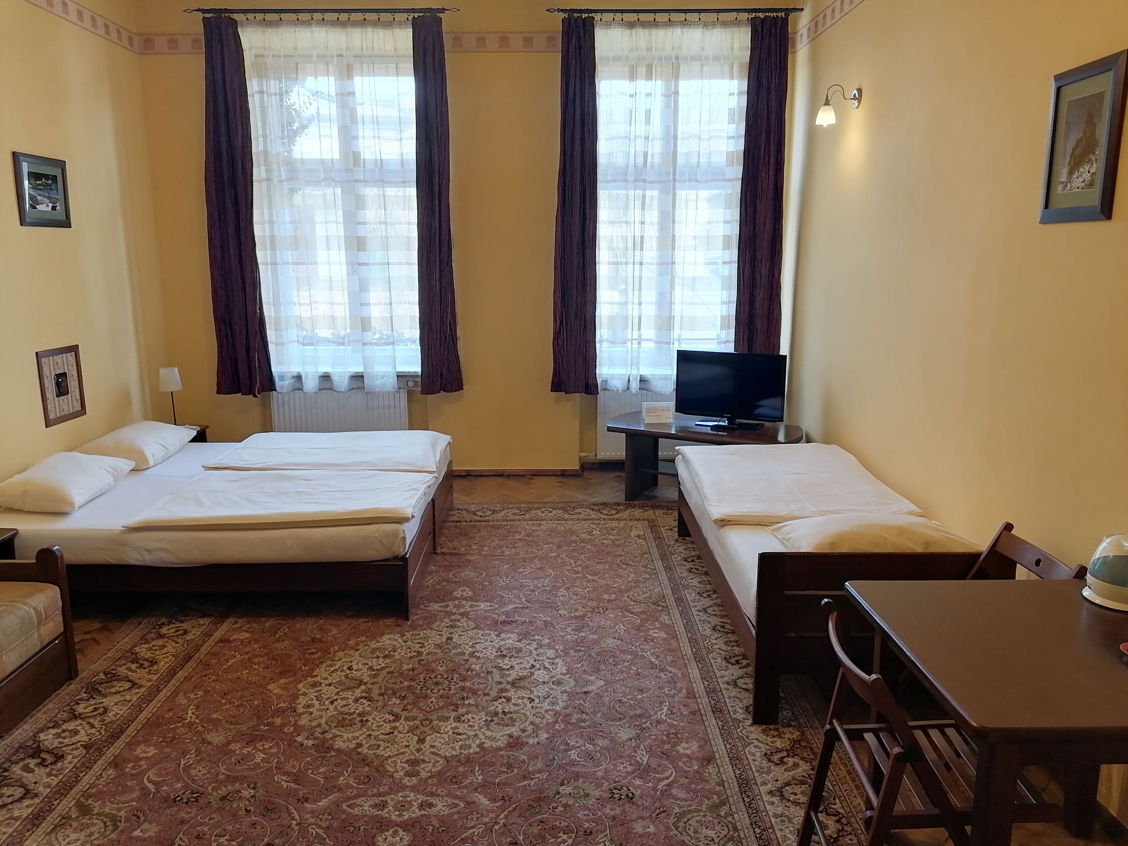 Une chambre d’hôtel avec deux lits simples, une télévision, un bureau et une chaise.