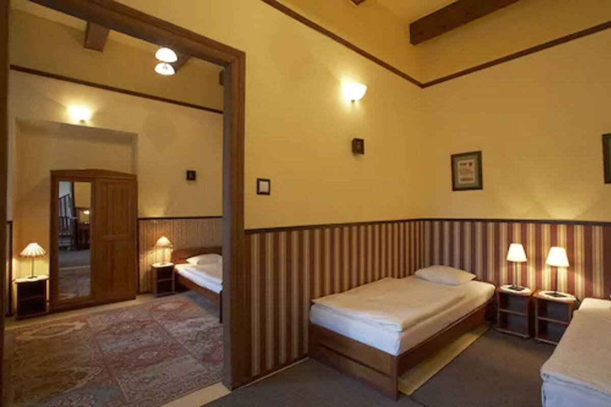 A hotel room with two single beds, a wooden headboard, a mirror, and a small rug.