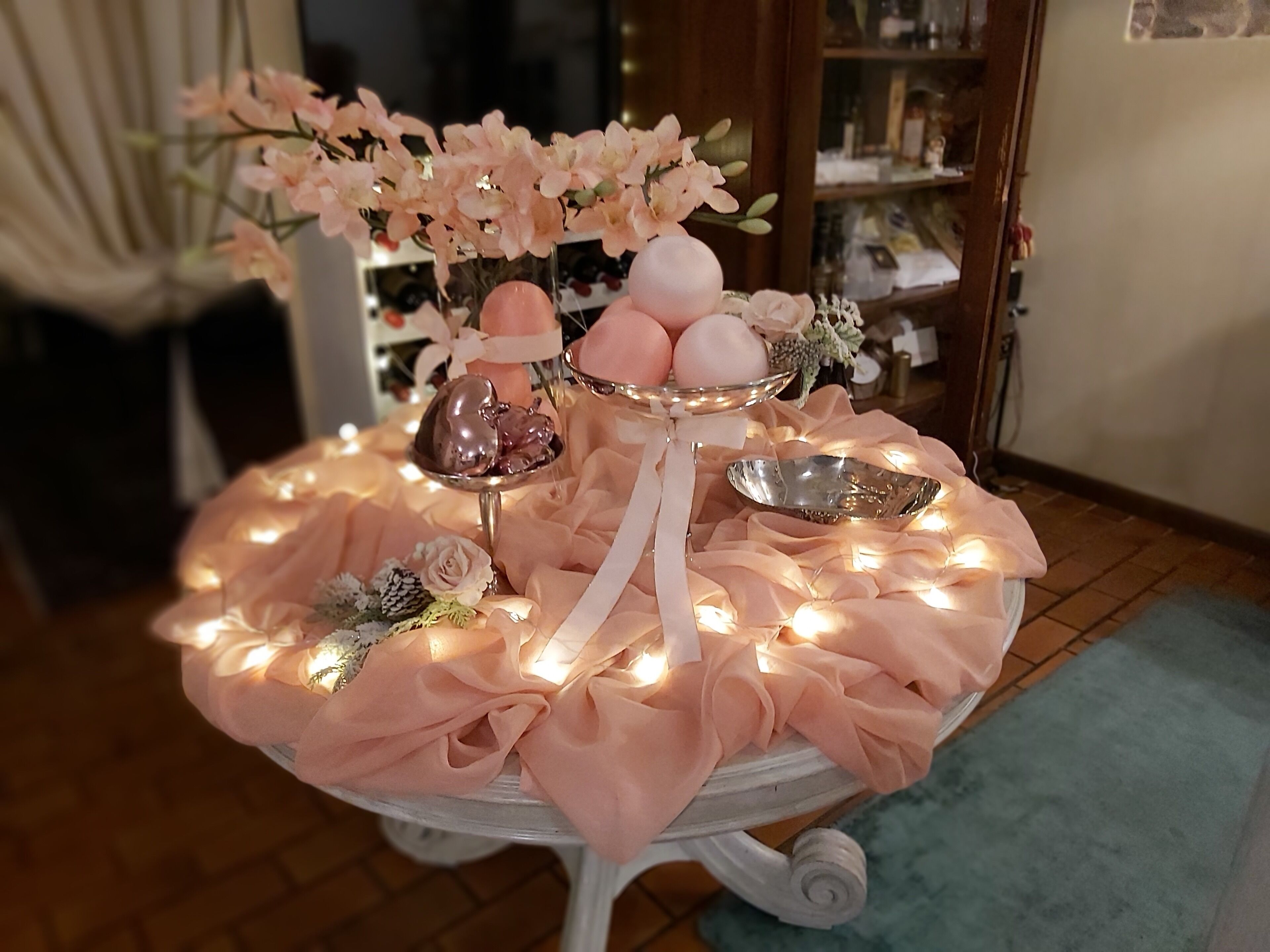 Ein Tisch mit rosa Blumen, einem dekorativen Teller und einer kleinen Statue.