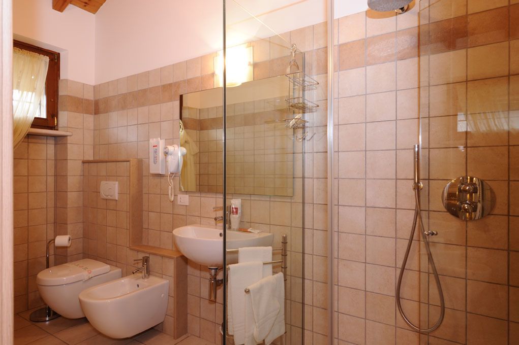 Ein Badezimmer mit Bidet, Waschbecken, einer Duschkabine aus Glas und einem Spiegel.