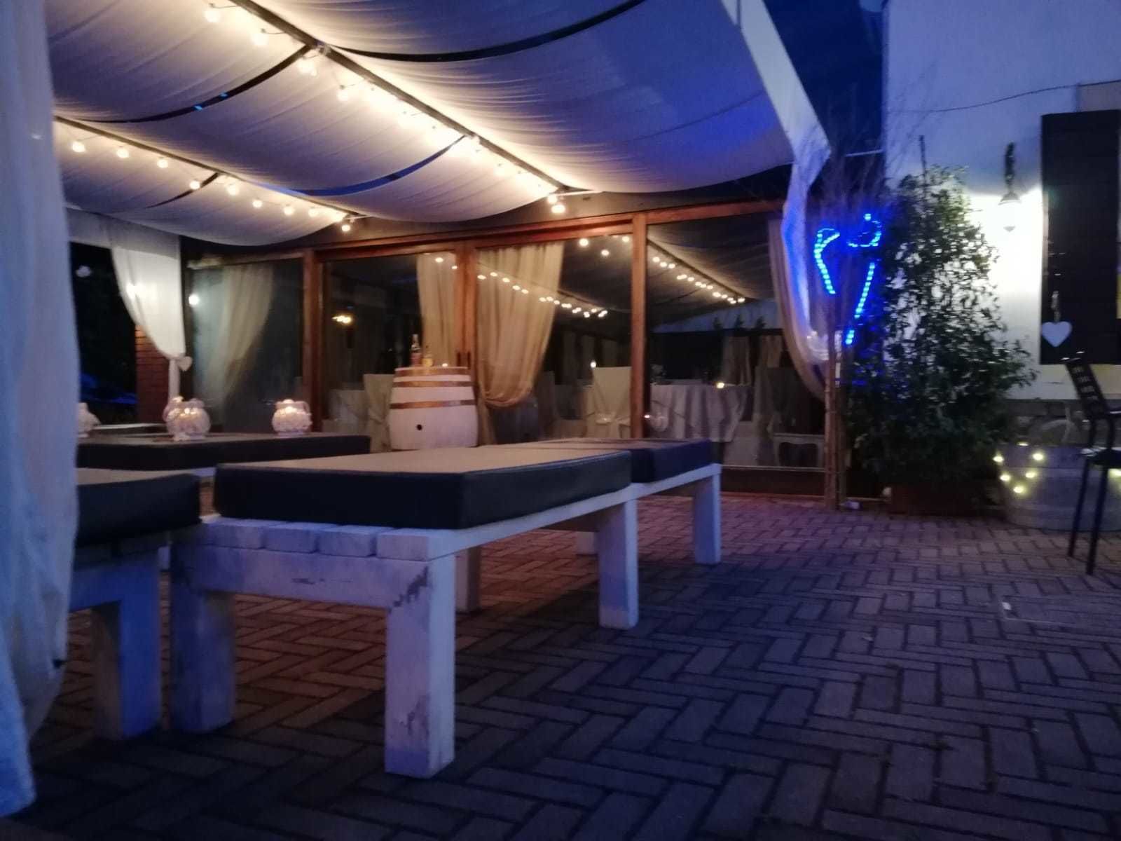 Un espace extérieur aménagé en patio, avec une table, des bancs, des guirlandes lumineuses et un sapin de Noël.