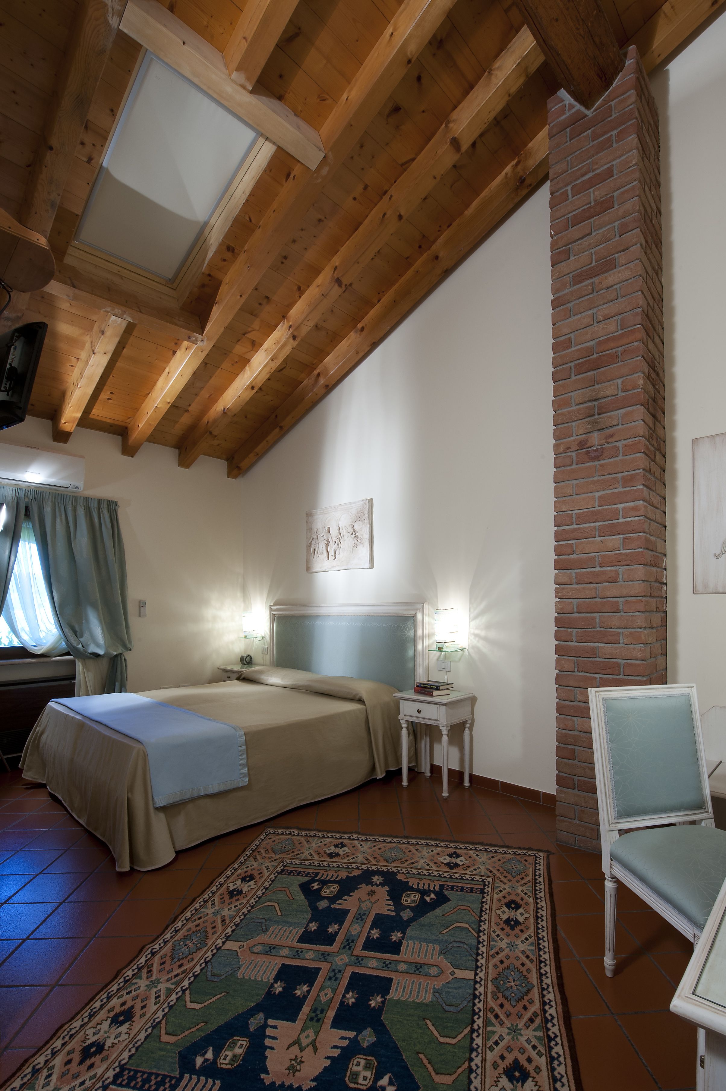 Une chambre confortable avec un lit, des lampes de chevet, un tapis et un mur en briques.
