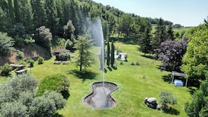 A landscaped garden with a fountain, picnic tables, and a swimming pool. - Resort la Mola (Sommacampagna)