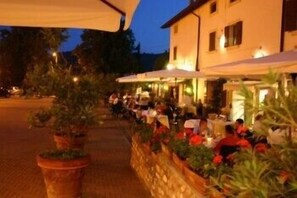An outdoor dining area with tables and chairs, surrounded by potted plants and a stone wall. - Resort la Mola (Sommacampagna)
